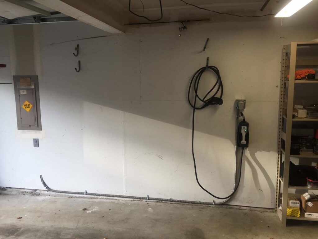 An electric vehicle charger and main electrical panel installed in a garage by Alt Electric LLC, serving Federal Way, WA.