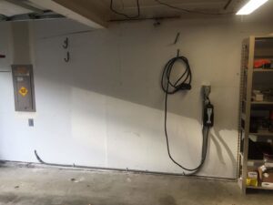 An electric vehicle charger and main electrical panel installed in a garage by Alt Electric LLC, serving Federal Way, WA.