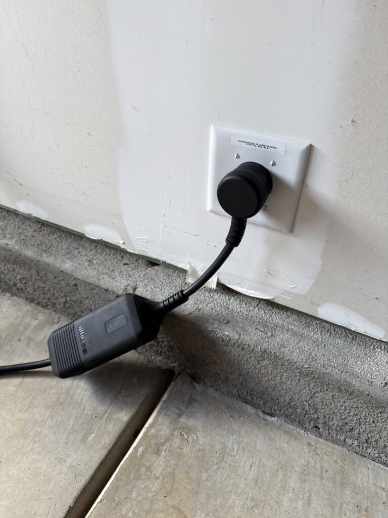 An EV charger plugged into a dedicated wall outlet in a garage by LivElectric in Garner, NC.