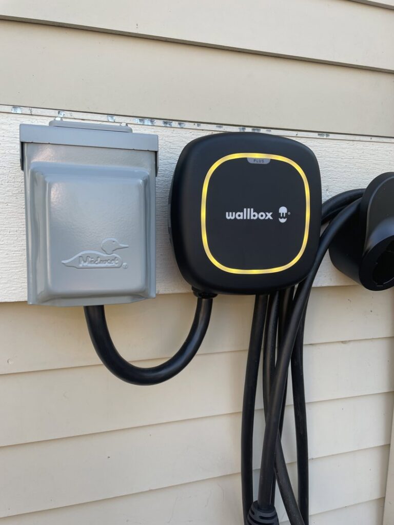 An outdoor Wallbox EV charger and disconnect box installed on house siding by Delatour Electric in Portland, OR.