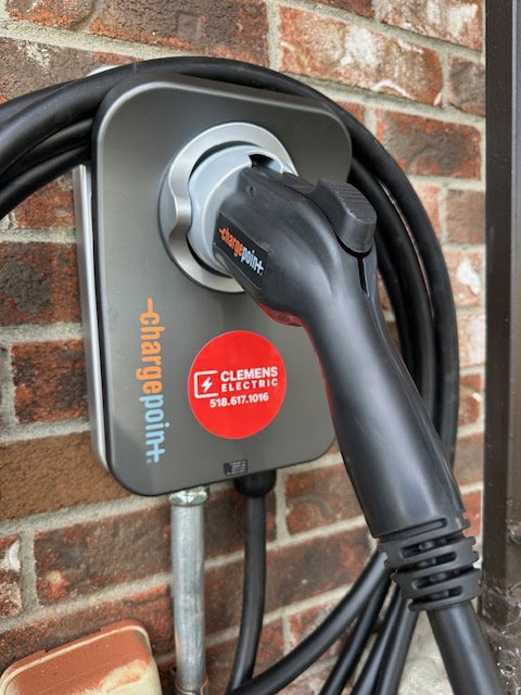 An EV charging station with a green light indicating use, installed by Clemens Electric in Averill Park, NY