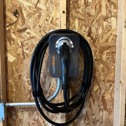 An electric vehicle charging station professionally installed on a wooden wall by Arnold Electrical Repair & Installation in Chicago, IL.