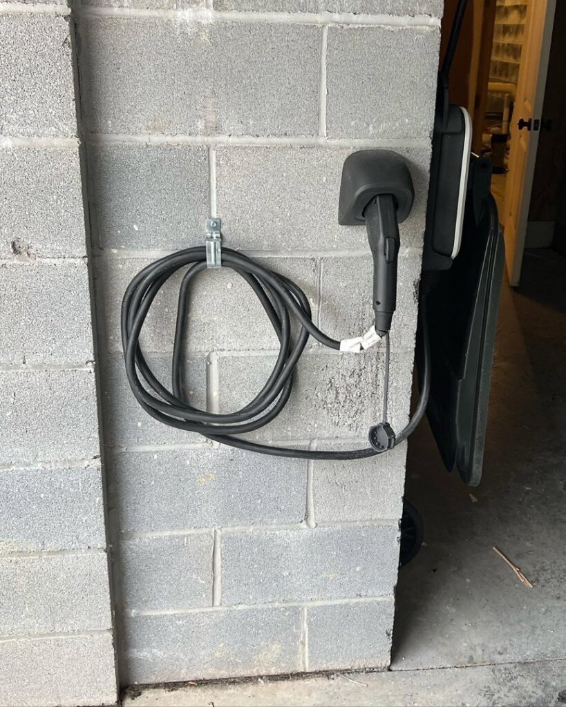 An installed electric vehicle charging station on a garage wall by Gloudeman Electric in Mount Pleasant, SC