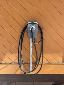 An electric vehicle charging station installed on a wooden wall by S & S Electric Service in Chepachet, RI.