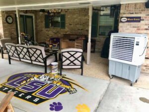 An evaporative cooler providing comfort on an outdoor patio with LSU branding by Cajun Kooling in Broussard, LA