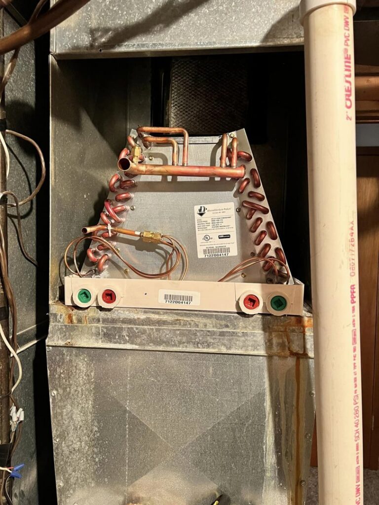An evaporator coil visible inside an HVAC system's plenum, indicating service or installation by Golden Heating and Air LLC in Arvada, CO.