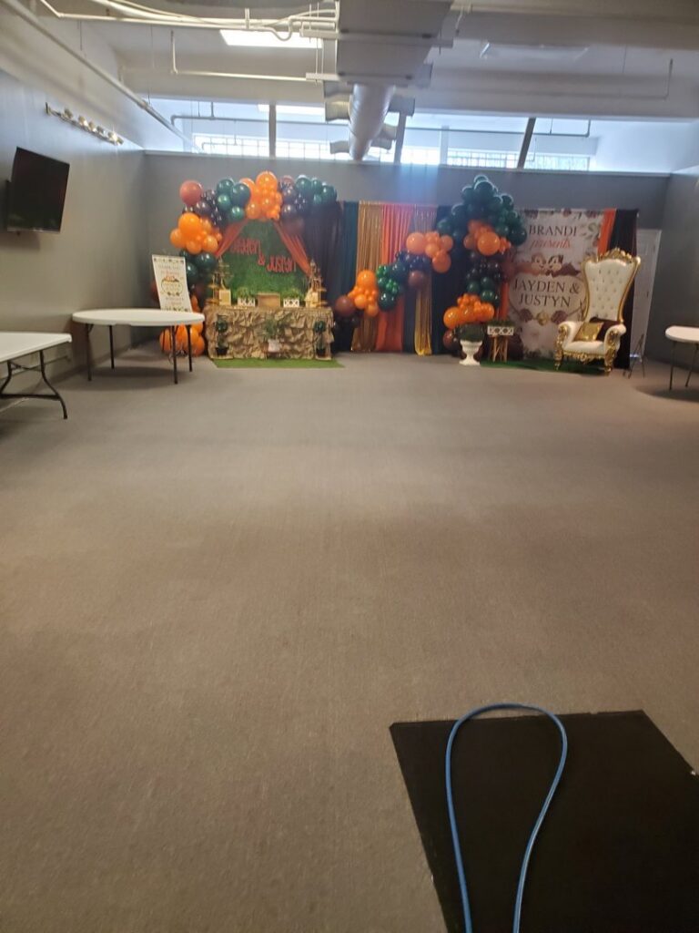 A large event hall with grey carpet and a cleaning hose, indicating professional service by Kingdom Kleen in Portsmouth, VA.