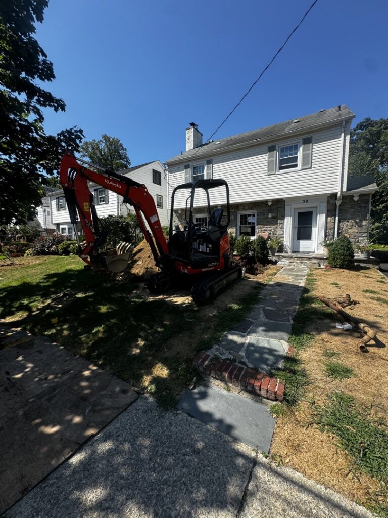 An excavator digging in a residential yard for a project by L&SON Heat AC Tech in Yonkers, NY.