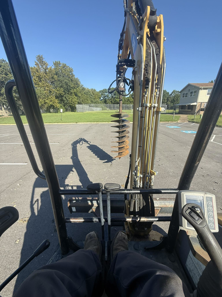 An excavator with an auger attachment used for digging holes for electrical infrastructure by Relay Electric, LLC in Suffolk, VA.