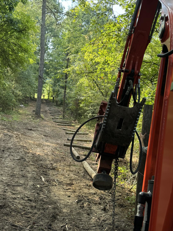 Excavator with post driver attachment installing fence posts by Smith Land and Farm in Mansfield, GA