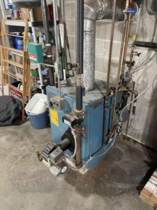 An existing boiler heating system in a basement, serviced by Aaron Hamilton Heating in Brunswick, ME.