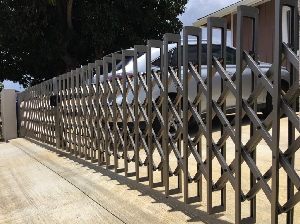 An expandable accordion-style driveway gate installed by KunkelWorks Hawaii in Mililani, HI.