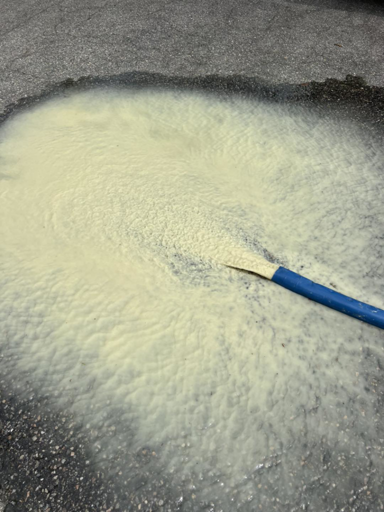 A hose expelling cloudy, yellowish water from a pool during cleaning by Pipeline Pools Inc. in Virginia Beach, VA.