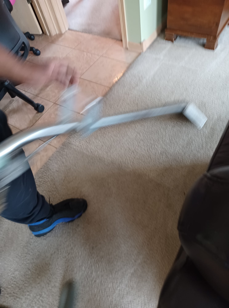 An expert carpet cleaner using a professional wand to clean a carpet, showing motion, by Hopman Rug Cleaners in Hammond, IN.
