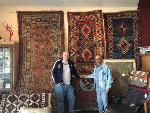 Two carpet experts carefully inspecting a large patterned rug for repair or cleaning at Ko-Z-Craft in Los Angeles, CA.