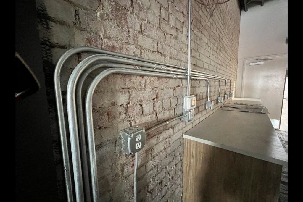 Exposed electrical conduit and outlets installed on a brick wall by Innovative Electric in Wichita, KS.