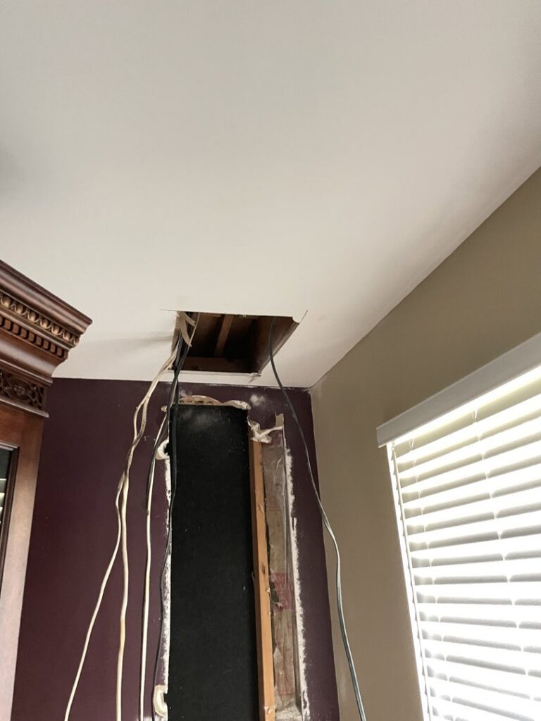 Exposed electrical wiring coming from a ceiling and wall opening, indicating ongoing electrical work by J. Bathe Electric in Saint Charles, MO.
