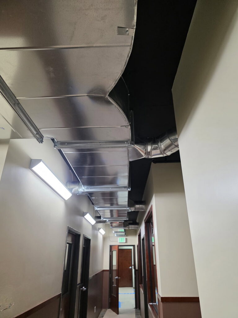 Exposed HVAC ductwork running along a commercial hallway ceiling, installed by Jons-Air in Carmel, IN.