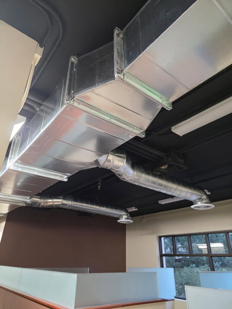 Newly installed exposed metal ductwork in a commercial ceiling, showcasing HVAC installation by Jons-Air in Carmel, IN.