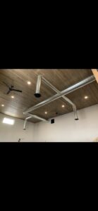 Exposed spiral ductwork installed on a finished ceiling by AP HVAC in Ridgewood, NY.