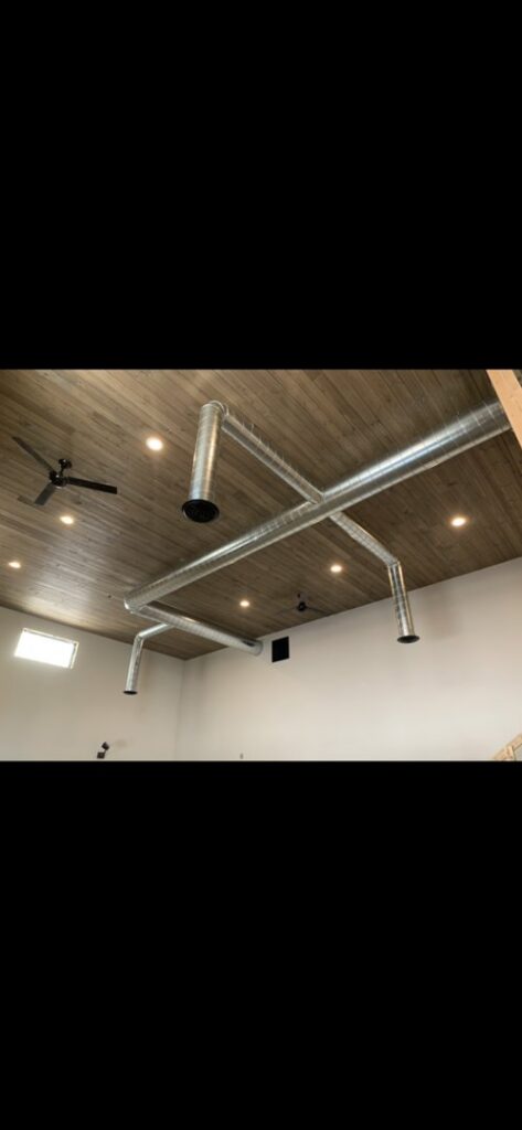 Exposed spiral ductwork installed on a finished ceiling by AP HVAC in Ridgewood, NY.