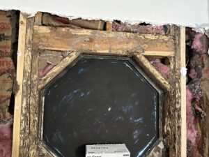 Extensive termite damage visible on the wooden framing around a window, revealing insulation, a problem handled by Next Level Pest Services in Fort Worth, TX.