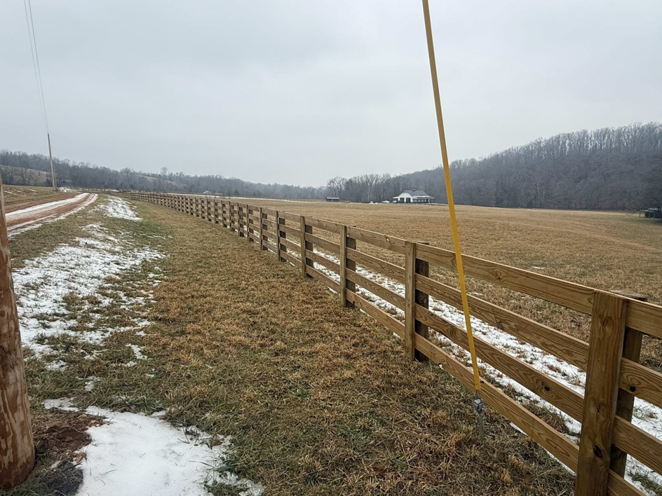 An extensive wooden field fence installation stretching across a snowy landscape by Richards Fencing in Lynnville, TN