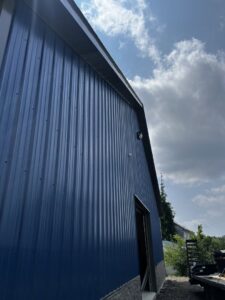 An exterior wall-mounted light fixture on a blue metal building, installed by Superior Electrical Solutions llc in Clear Spring, MD.