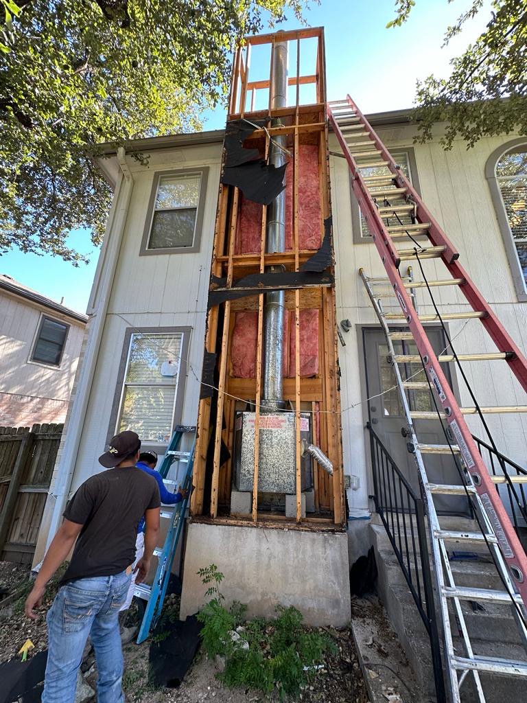 Exterior chimney repair and construction in progress with ladders at a home by The Texan Chimney Sweep San Antonio, TX.