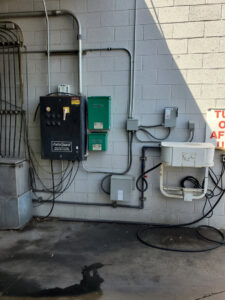 Exterior commercial electrical panels and conduits on a brick wall, installed by TJS Electrical Services Inc in Mesa, AZ.