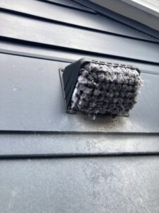 An exterior dryer vent cover completely blocked by lint, demonstrating the importance of dryer vent cleaning by Star Quality Air Duct Cleaning in Silver Spring, MD.