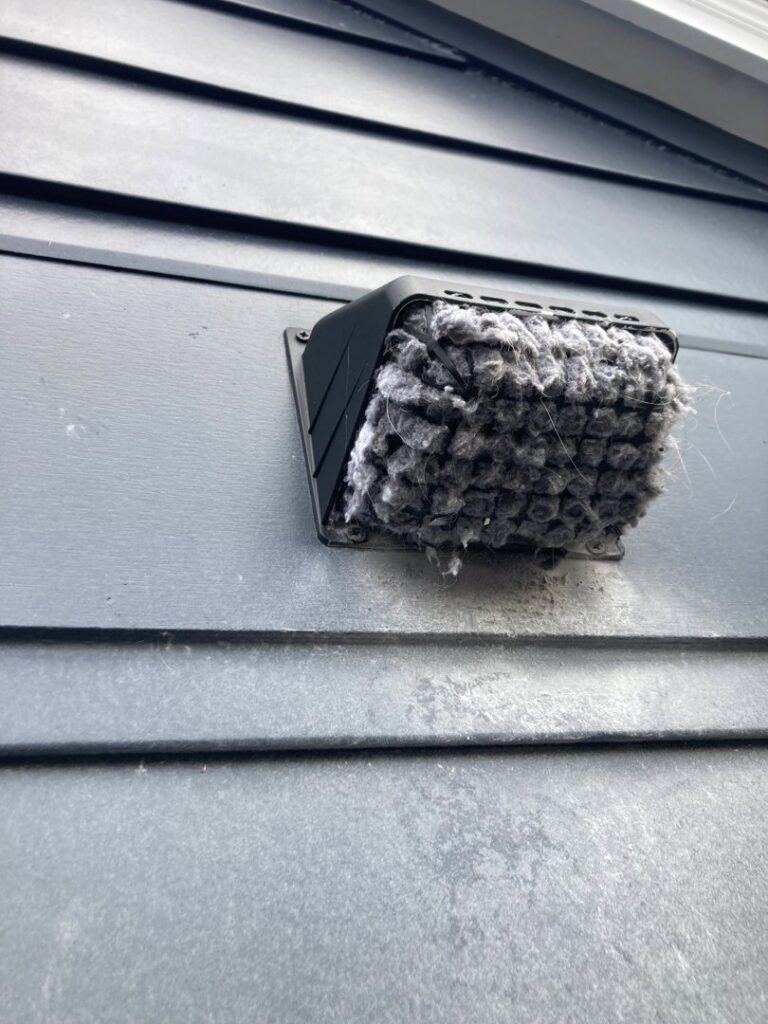 An exterior dryer vent cover completely blocked by lint, demonstrating the importance of dryer vent cleaning by Star Quality Air Duct Cleaning in Silver Spring, MD.