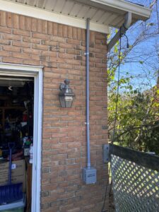 Exterior electrical conduit and a connection box installed on a brick wall, demonstrating work by Peak Electric in Mount Washington, KY.