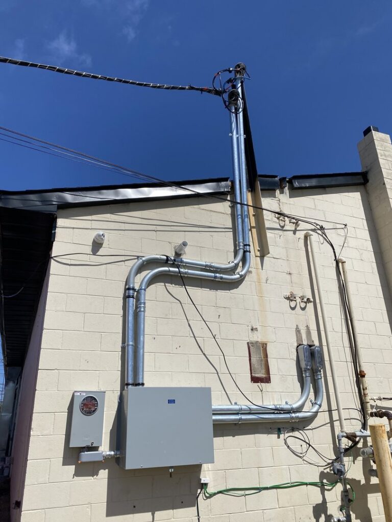 Detailed view of exterior electrical conduit and service mast installation by BYLIS Electric LLC in Allentown, PA.