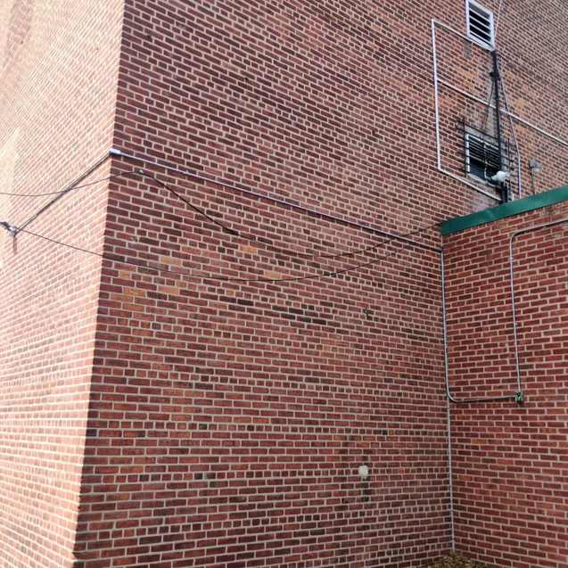 Exterior electrical conduit professionally installed on a brick building by C&J And Sons Multi Services in Newark, NJ.