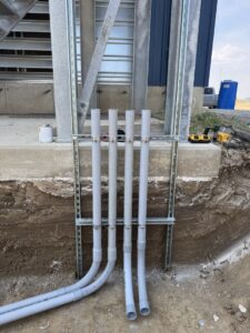 Exterior electrical conduit installation leading into the ground, performed by Delta Current Electric in Jonesboro, AR.