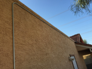 Long run of exterior electrical conduit installed on a building wall by Earth Electric in Mesa, AZ