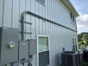 Exterior electrical conduit and meter installation on a modern building by Grounded Electric LLC in Smithfield, VA.
