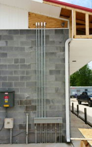 Exterior electrical conduit and panel installation on a cinder block wall by Ready Electric 24/7 in Knoxville, TN.