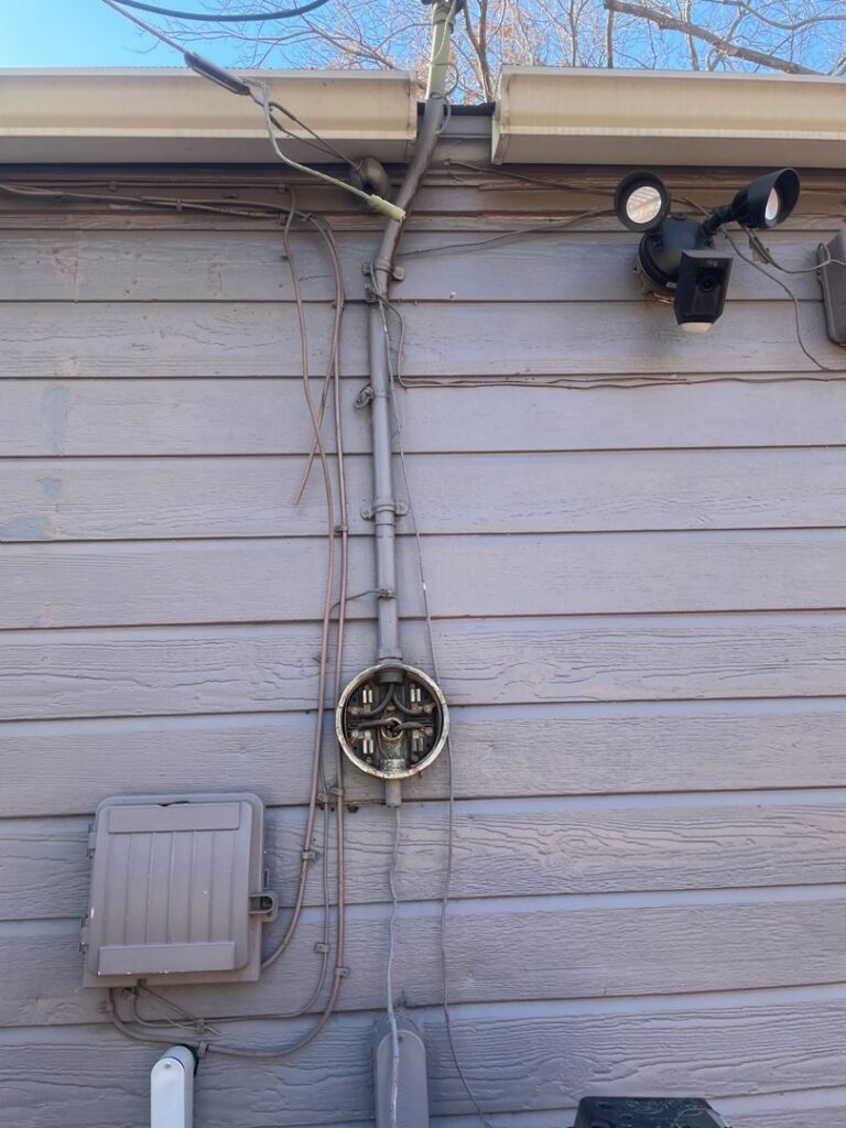 Exterior electrical conduit and meter base on a house wall, serviced by AVA Electric, LLC in Fort Worth, TX.