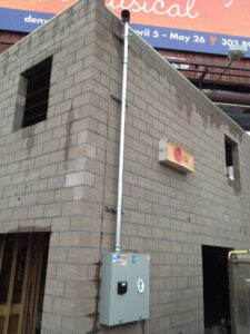 Exterior electrical conduit and meter box installation by Black Bear Electric on a brick building in Aurora, CO.