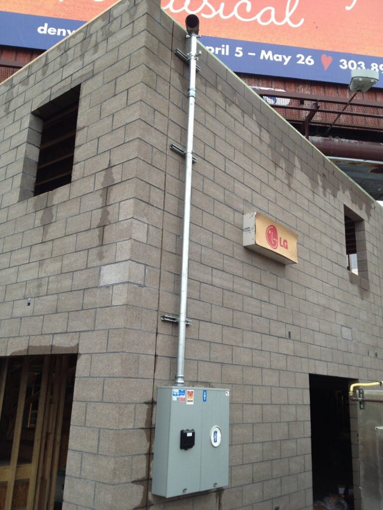 Exterior electrical conduit and meter box installation by Black Bear Electric on a brick building in Aurora, CO.