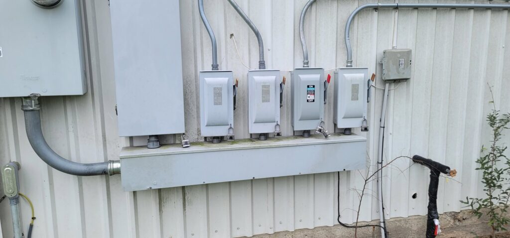 Multiple exterior electrical disconnect switches installed on a corrugated metal wall by Ponce Electric in Houston, TX