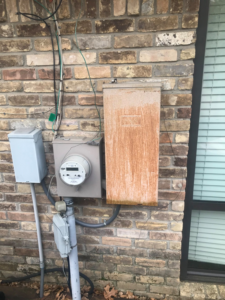 Exterior electrical meter and service boxes on a brick wall by Pressed Down Electric LLC in Rockwall, TX.