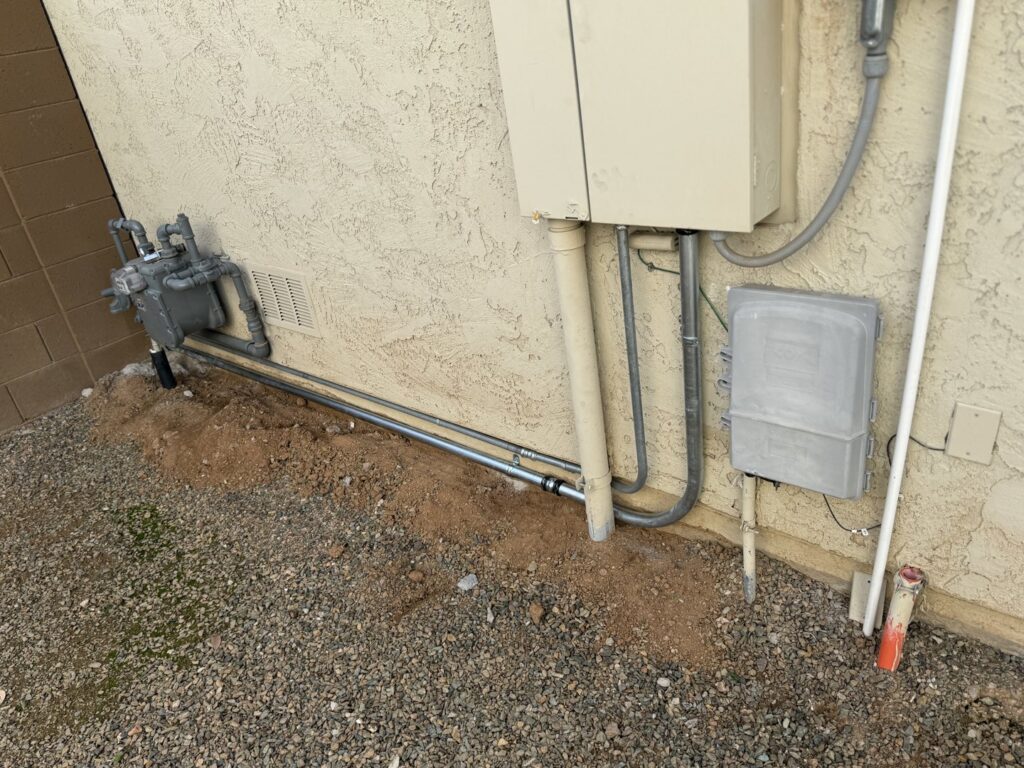 Exterior view of electrical meters and conduit installation alongside gas lines by Sparks By Rabbit LLC in Scottsdale, AZ.