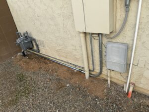 Exterior view of electrical meters and conduit installation alongside gas lines by Sparks By Rabbit LLC in Scottsdale, AZ.