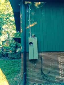 An exterior electrical meter and conduit installed on the side of a house by Volt Doctors in Durham, NC