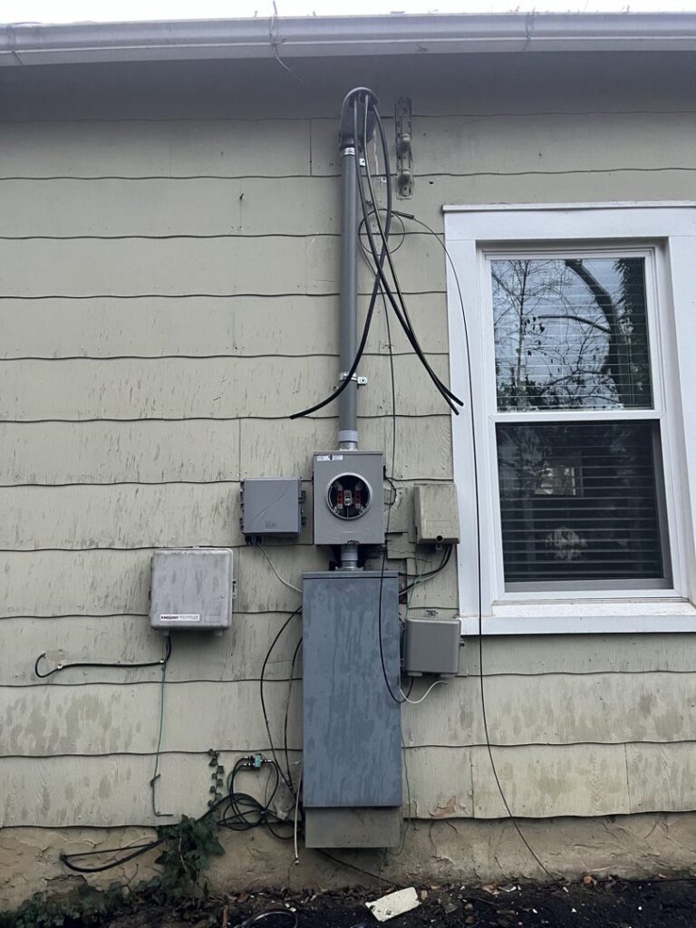An exterior electrical meter and conduit installation on the side of a house by Mayflower Electric LLC in Knoxville, TN
