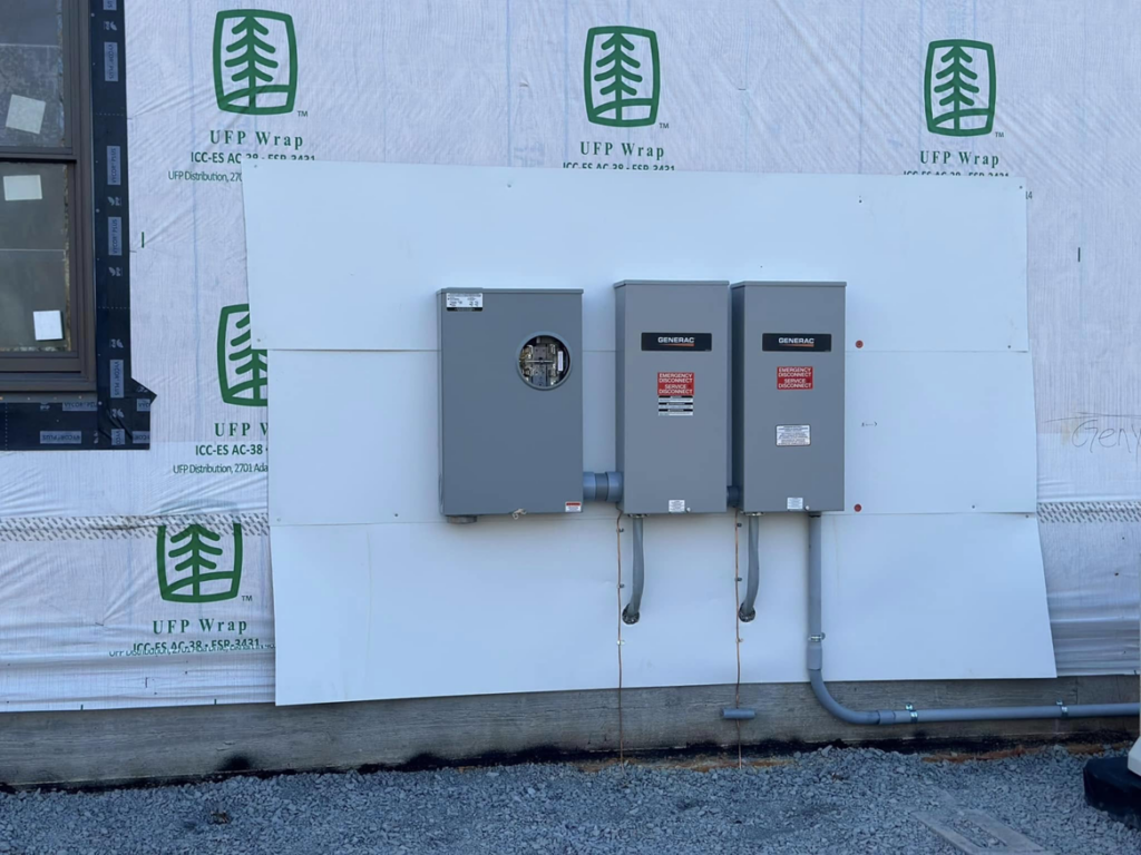 Exterior electrical meter and two Generac transfer switches installed on a building under construction by Moser Electric in Wisconsin Rapids, WI.