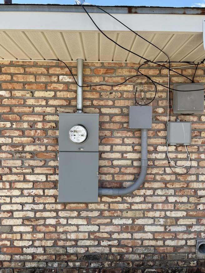 An exterior electrical meter and conduit system installed on a brick wall by Greater Baton Rouge Electric in Baton Rouge, LA.